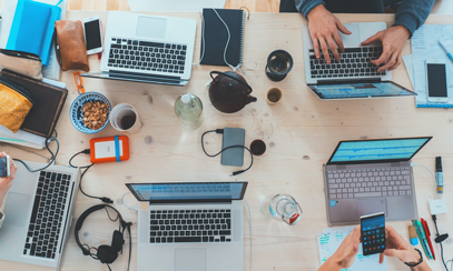 On the table are laptops, smartphones, various devices